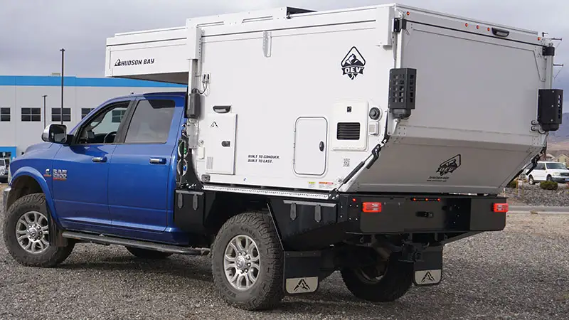Blue Ram with its truck bed replaced by a 6.75 foot Aluma Tray flatbed, carrying a white hard side truck camper
