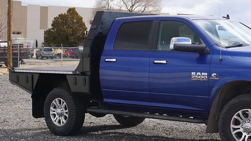 Blue Ram 2500 crew cab fitted with a 6.75 foot Aluma Tray aluminum flatbed, side view of the empty deck and tapered black bulkhead