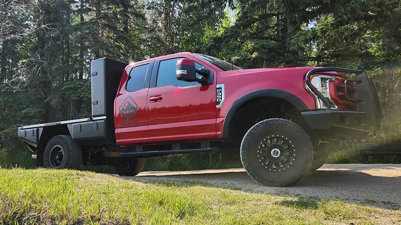 Side view of a red Ford Super Duty with an 8 foot Aluma Tray and a deck mounted spare tire