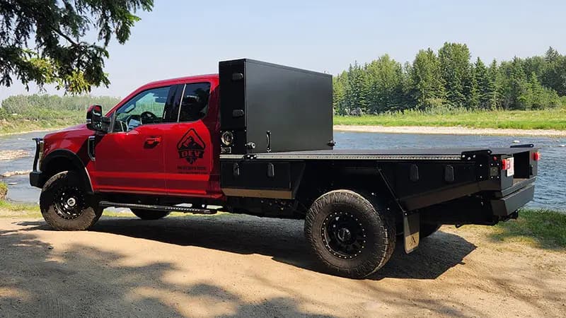 Side profile of a red Ford Super Duty with an 8 foot Aluma Tray, parked by the water