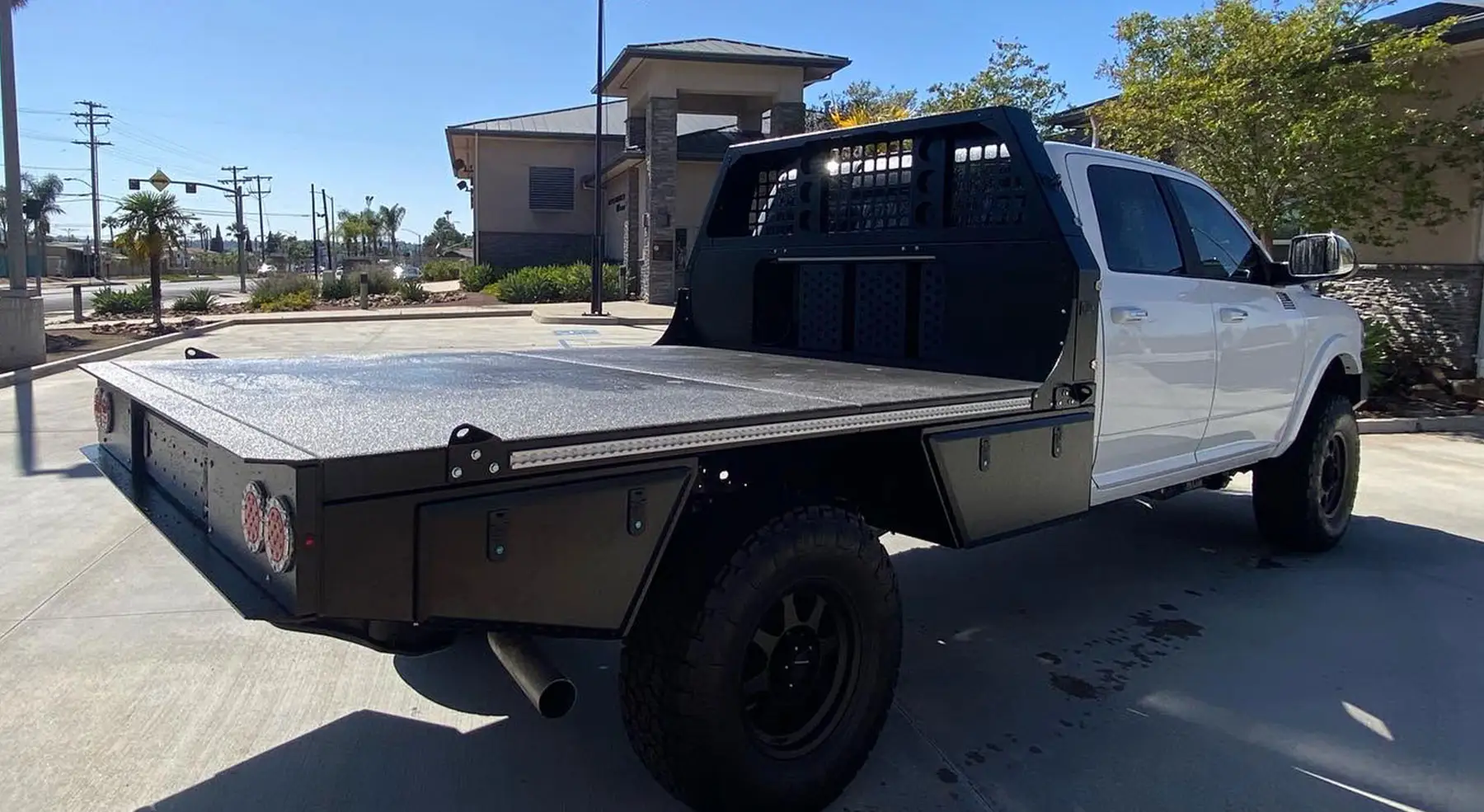 White Ram chassis cab with an Aluma Tray HD-60 chassis cab flatbed, rear three quarter view